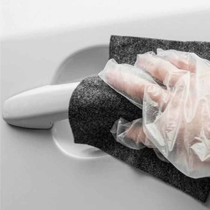 Hand in a glove buffing a scuff near a car door handle with the NanoPolix cloth